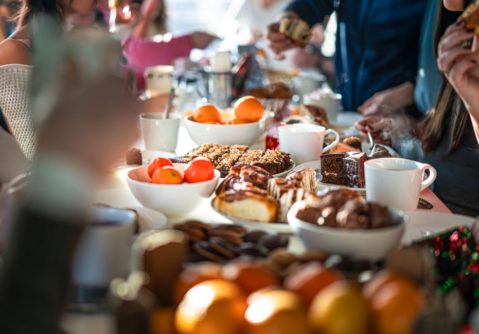 People seated around a breakfast table with coffee and pastries.